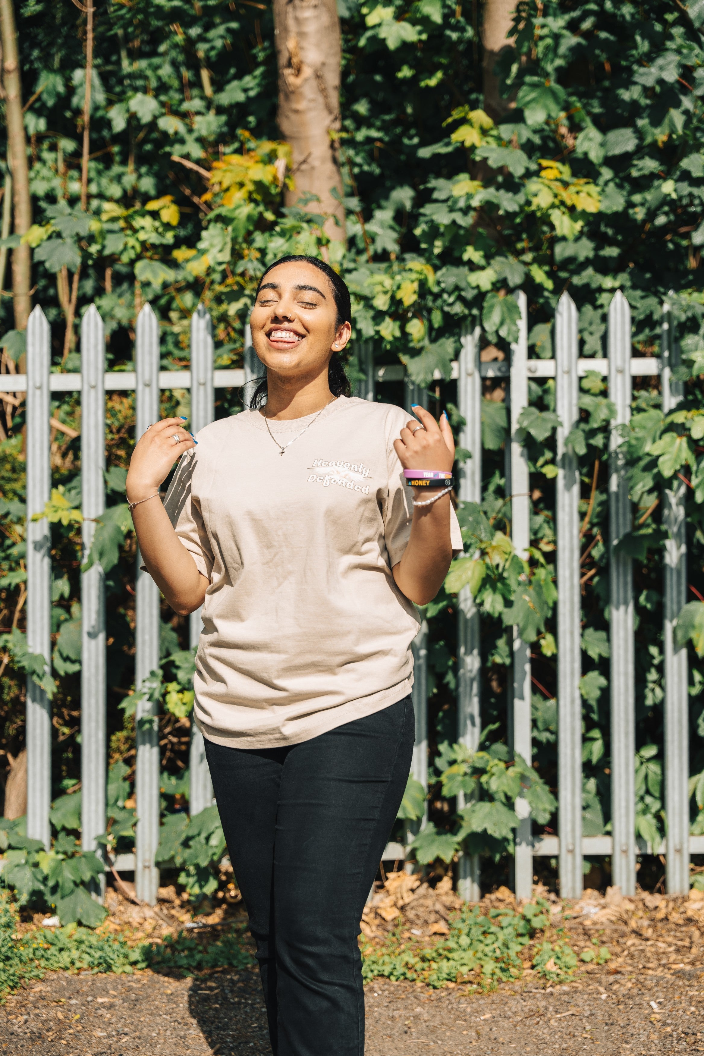 Woman walking outdoors with a white picket fence and greenery in the background